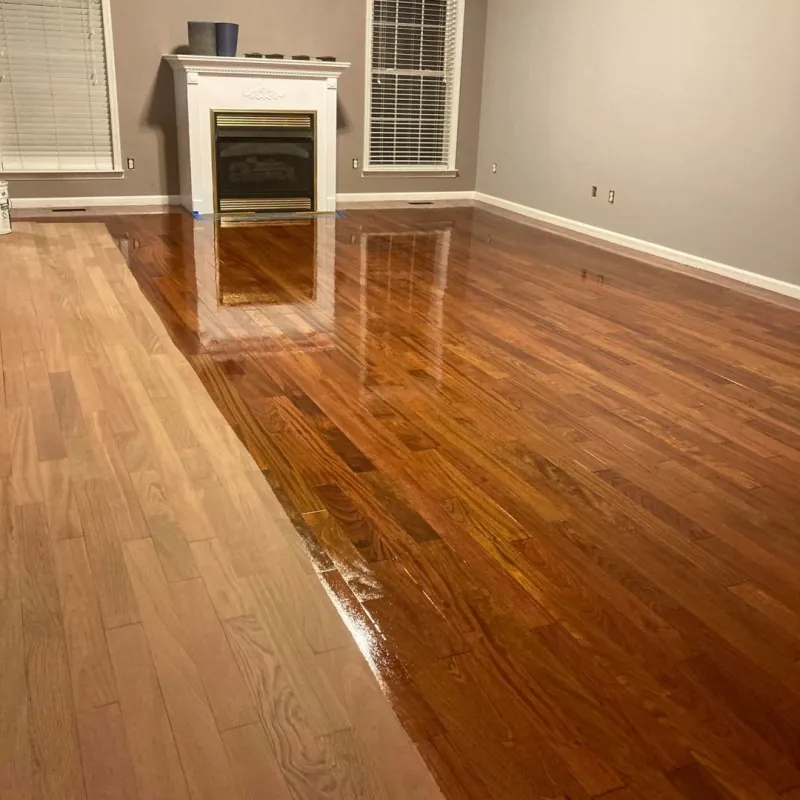 Glossy hardwood floor in a living room with a fireplace and a bright reflective finish