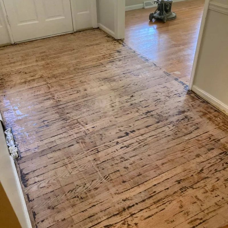 Worn hardwood floor with dark stains and scuffs before sanding and refinishing