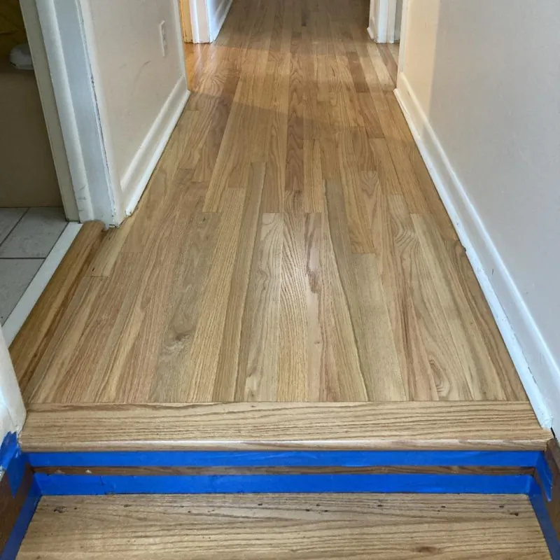 Refinished oak hardwood hallway with a clean light finish and white trim